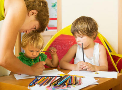严肃的母亲和孩子用铅笔画画