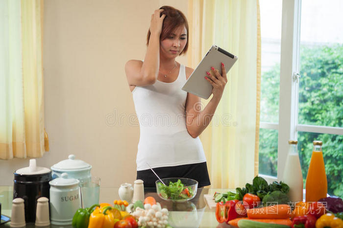 年轻女子在数字平板电脑上跟随食谱