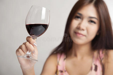 美丽的亚洲女人拿着一杯红酒专注于酒杯