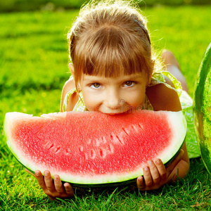 可爱的小西瓜可爱的小女孩吃着西瓜躺在绿草地上照片