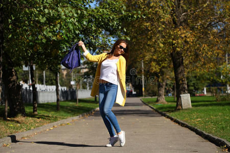 穿着黄色外套的快乐女人走在秋天的大街上