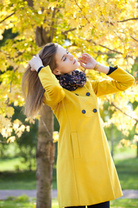 秋天街上穿着黄色外套的快乐年轻女子