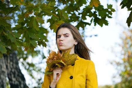 秋天公园里穿着黄色外套的快乐年轻女子