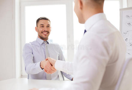 两个微笑的商人在办公室握手