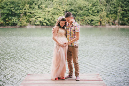 年轻的孕妇和丈夫站在湖边