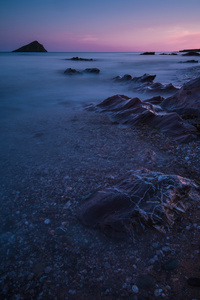 在黄昏的岩石海滩上，温暖而宁静的海景与黑暗的运动模糊