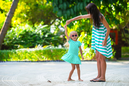 可爱小女孩和热带海滩假期的快乐妈妈