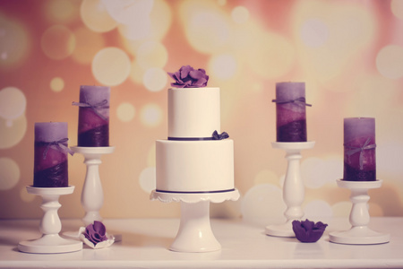 白色婚礼蛋糕 sorounded 由紫色蜡烛