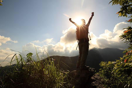 拉伸欢呼在山顶悬崖张开双臂欢呼的女子徒步旅行者照片