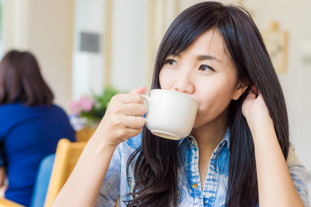 年轻可爱的亚洲女人喝咖啡