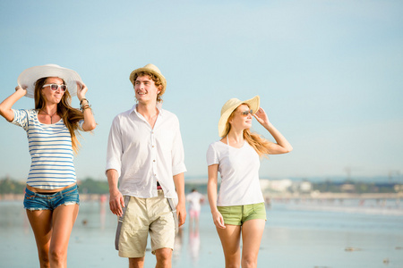 群快乐的年轻人走在沙滩上美丽的夏天日落