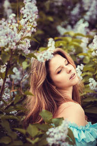 美丽的女人享受丁香花园，年轻女性的花在绿色公园。性格开朗的青少年走户外。软光风格颜色