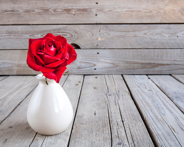 木制的桌子上插在花瓶里的红玫瑰