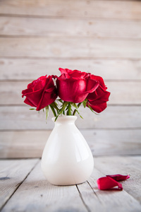 木制的桌子上插在花瓶里的红玫瑰
