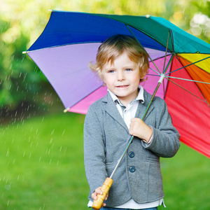 小可爱宝宝男孩与花伞和靴子，户外