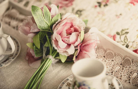 复古风格的照片粉红色的花躺在托盘上与茶杯