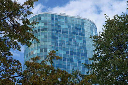 一座美丽的蓝色玻璃办公楼，周围环绕着树木