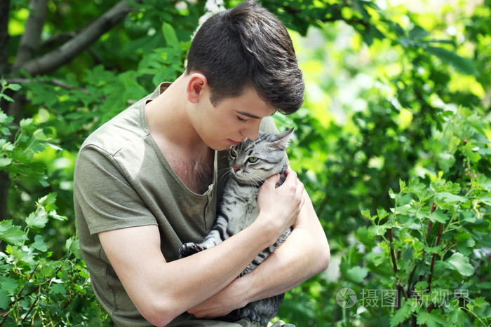 英俊的年轻男子与可爱猫咪在户外
