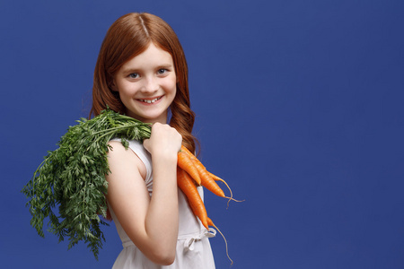 小女孩微笑着拿着胡萝卜束