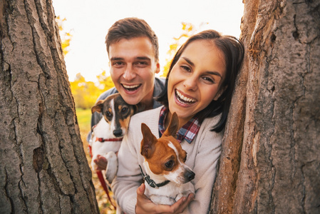 狗在户外的秋园中快乐年轻夫妇的肖像