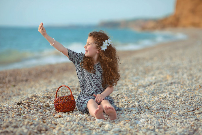 有趣的小女孩,用长长的卷发在沙滩上休息.出