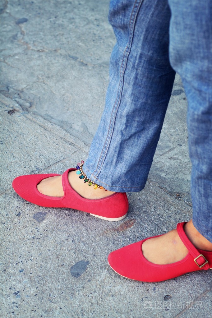 一位穿着红色鞋子和牛仔裤的女人