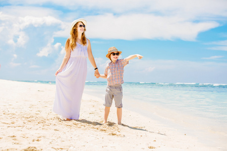 母亲和儿子沿着白沙滩散步，有一个大家庭