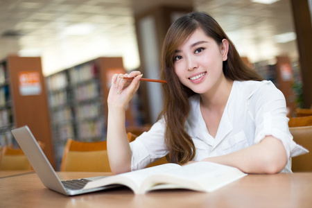 女留学生在图书馆与笔记本电脑