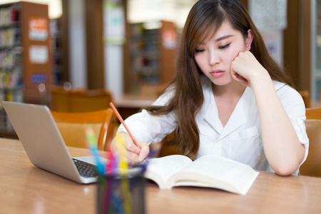 女留学生在图书馆与笔记本电脑