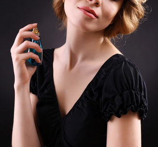 美丽的年轻女子，与黑色背景上的香水瓶