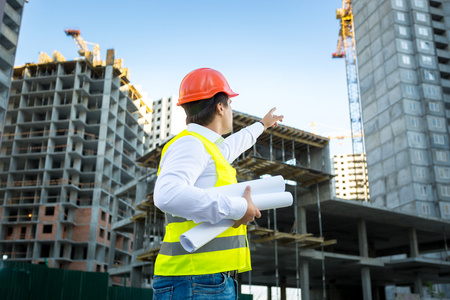 Hardhat的经理指着建筑工地上的起重机