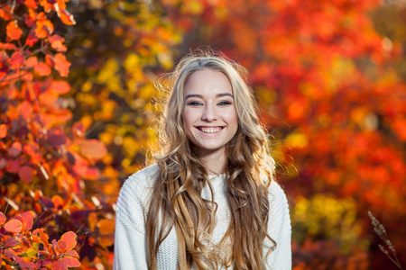 美丽的年轻女子，卷发的背景下，红色和黄色的秋天叶子，幸福，笑声微笑