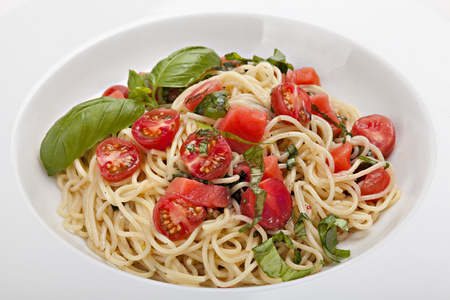 一盘带新鲜西红柿和罗勒的意大利面。