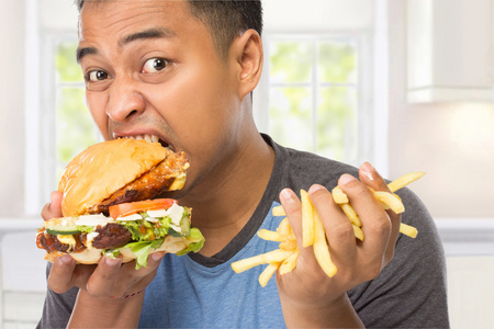 年轻人美味地咬着他的大汉堡照片