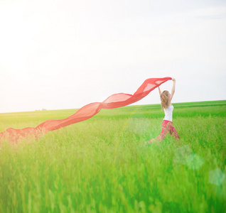 年轻的女士在绿色的田野里拿着纸巾奔跑。 女人和红疤