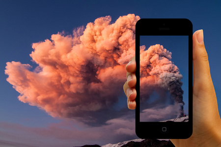 游客在智能手机上拍摄火山爆发图片