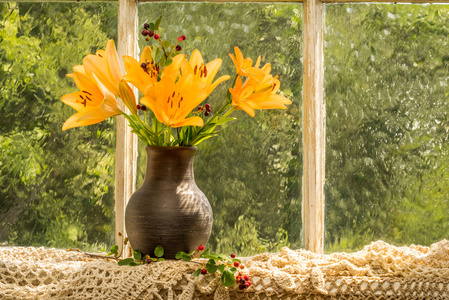 亚洲百合橙色枝百合花束在阳光下雨天的窗台上。橘黄色的好心情情绪