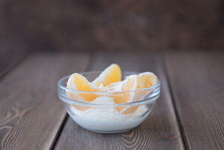 酸奶和橙片在木制的桌子上的玻璃盘