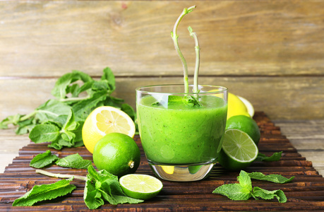 杯薄荷和水果木制背景上的绿色健康果汁