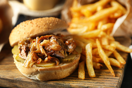 美味的汉堡和薯条上木桌背景板上。不健康食品的概念
