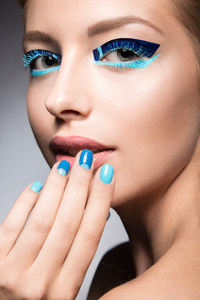明亮的创意时尚化妆和蓝色指甲油的漂亮女孩。艺术美设计