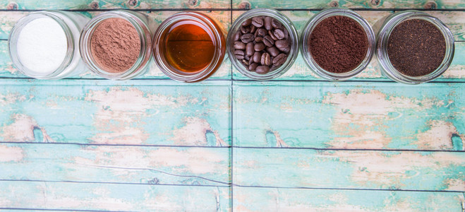 咖啡豆咖啡粉奶油可可粉蜂蜜和经过加工的茶叶放在石匠罐子里，放在风化的木质背景上