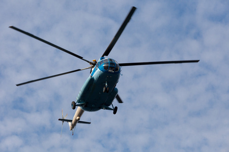 直升机飞行反对蓝色的天空和云