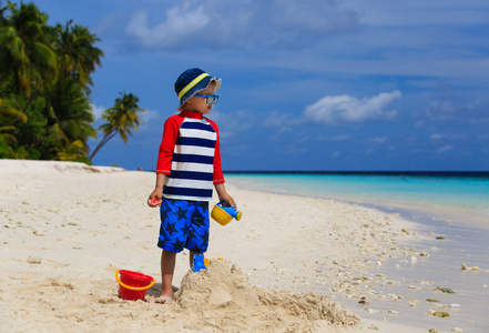 小男孩建设热带海滩上的堆沙堡