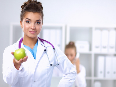 一位女医生手拿着一个绿色的苹果，站