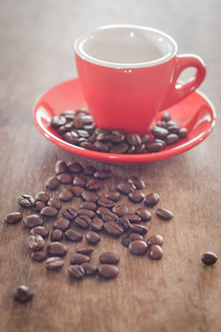 木制的桌子上的咖啡豆的红色咖啡杯