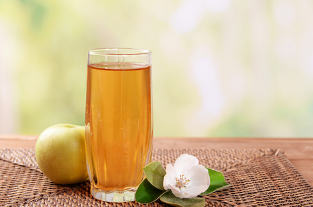 杯苹果汁和苹果在木桌前，在自然背景