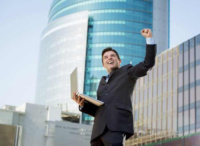 成功的商人与电脑笔记本快乐做胜利的手势