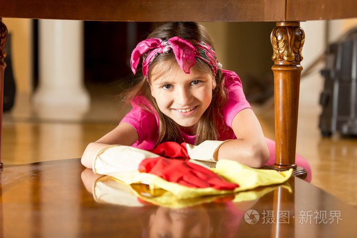 小女孩微笑着抛光用布木桌的肖像