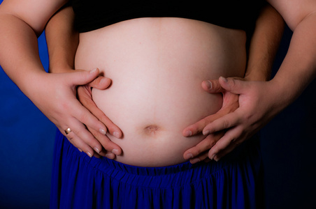 手男性和女性在怀孕的肚子
